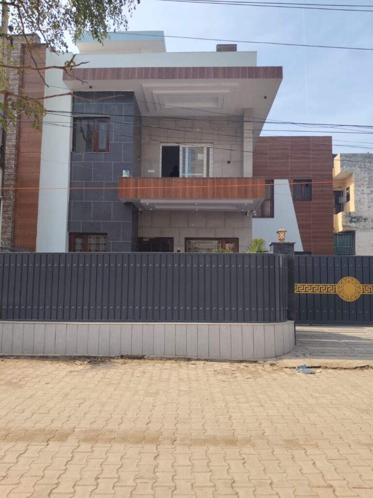 Modern two-storey residential house with grey stone cladding, wooden accent panels, balcony, and a dark grey front gate.